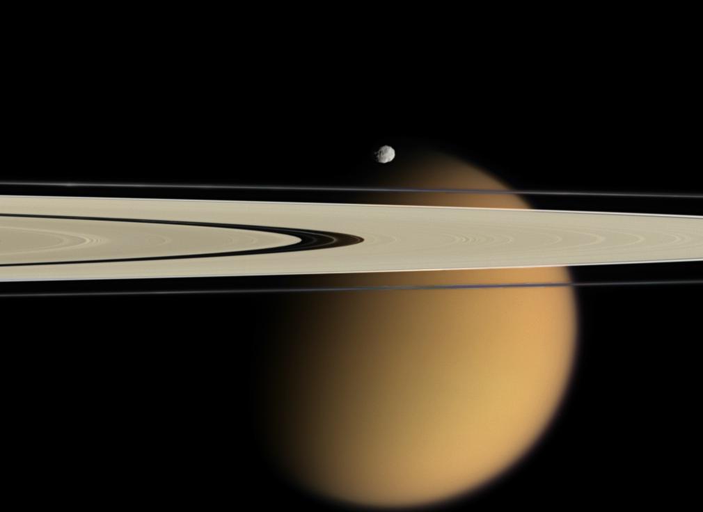 土星环和泰坦。背景中的巨大的模糊天体是泰坦，而土星环上方的形状奇特的天体是土卫十一（厄庇墨透斯，Epimetheus）（来源 NASA/JPL/Space Science Institute）